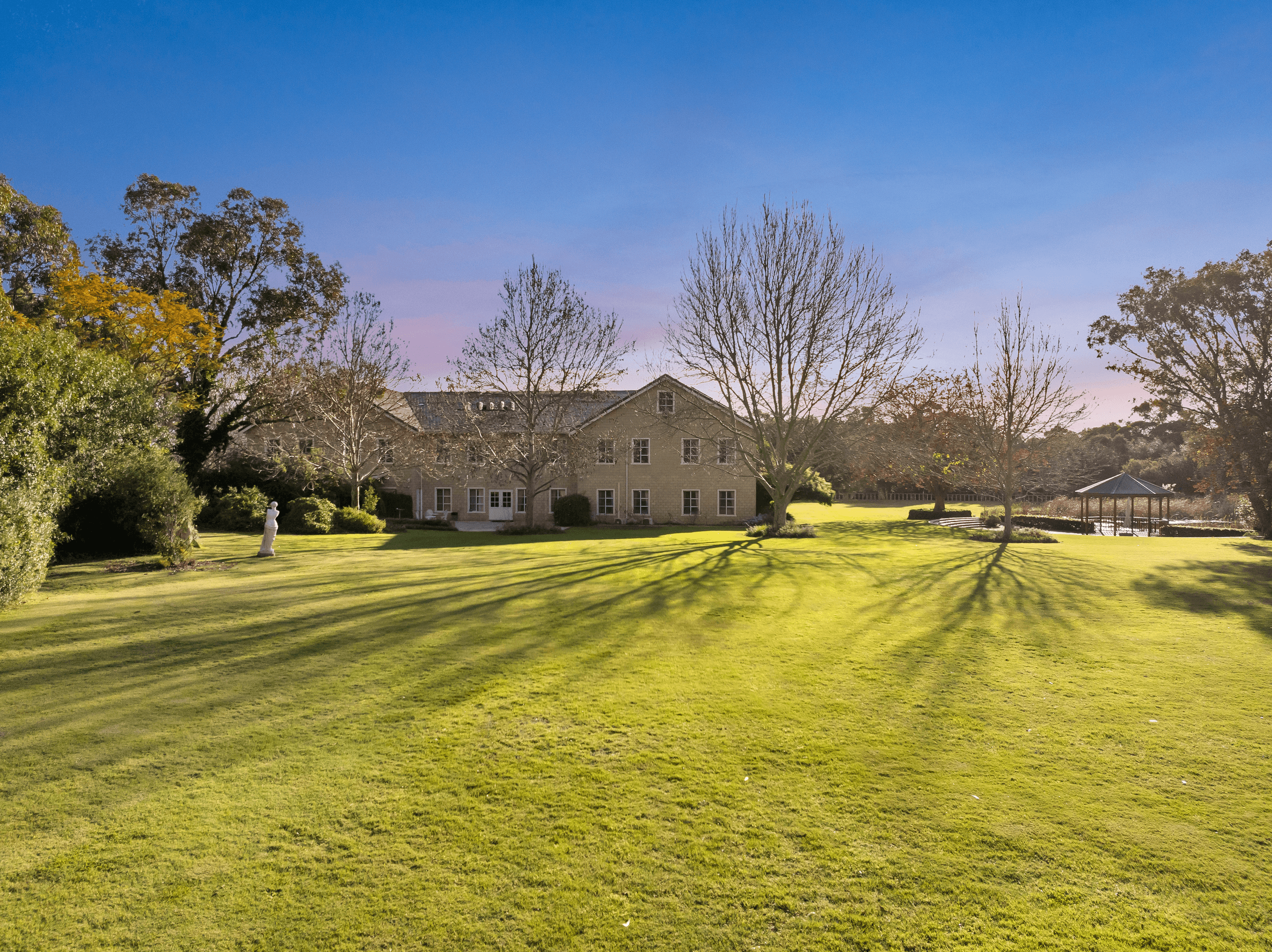 Peel Manor House and lawns at golden hour, with garden statue and gazebo