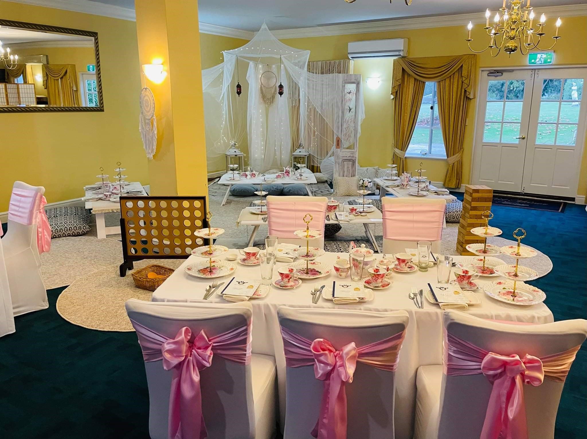 Boho-styled baby shower set-up in the manor's function room, with a fairy-light canopy, floor cushions and vintage tea table settings
