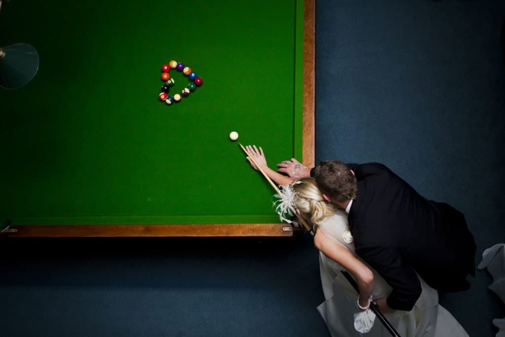 Overhead view of the bride and groom playing pool together in the manor's billiards room