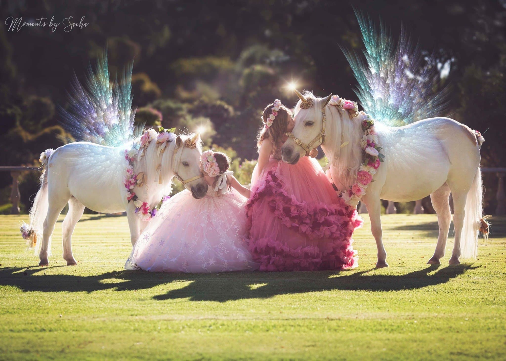 Two children in costume beside two ponies decorated as unicorns on the lawn — not a wedding photo