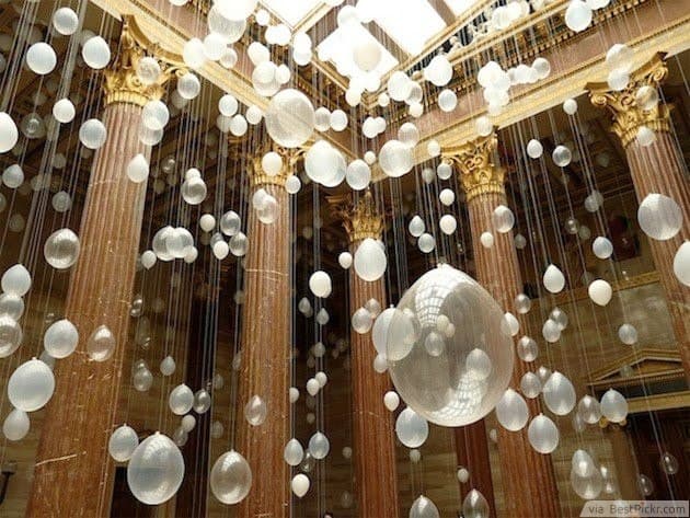 Stock photo of a hanging white balloon installation in a marble, gold-columned hall — a decorative reference image, not Peel Manor House